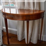 F19. Banded mahogany demilune table. Made in England. 29”h x 26”w x 16”d 